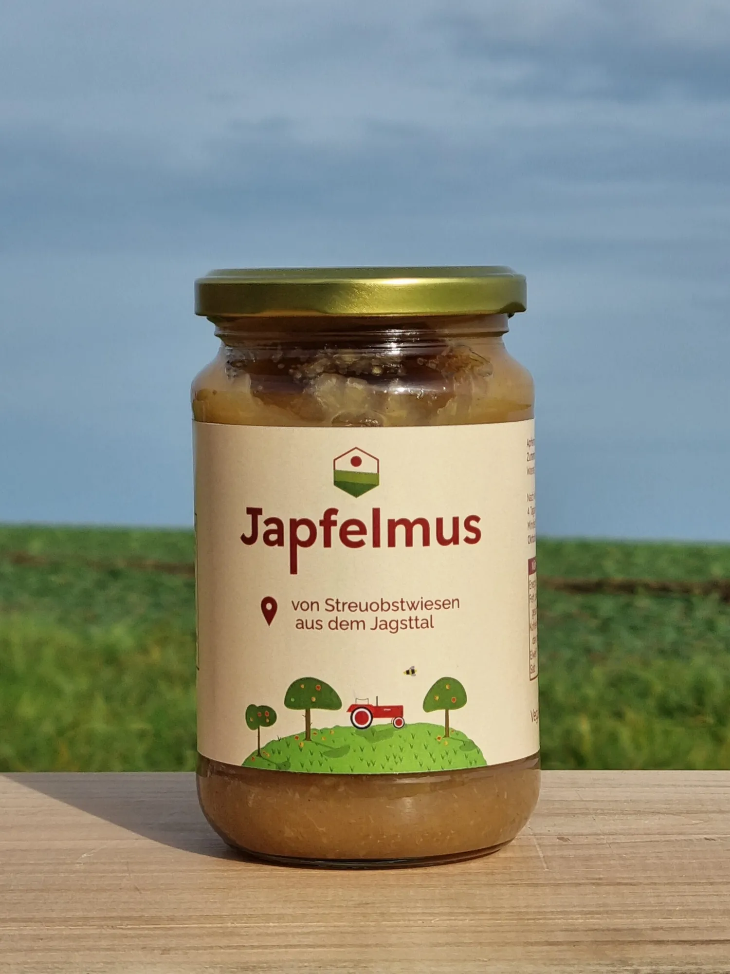 Ein Glas Japfelmus aus der Saison 2024 steht auf einem Holzbrett