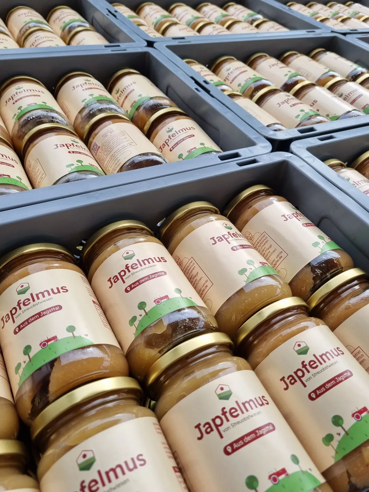 Viele aneinander gereihte Kisten mit Japfelmus Gläsern.